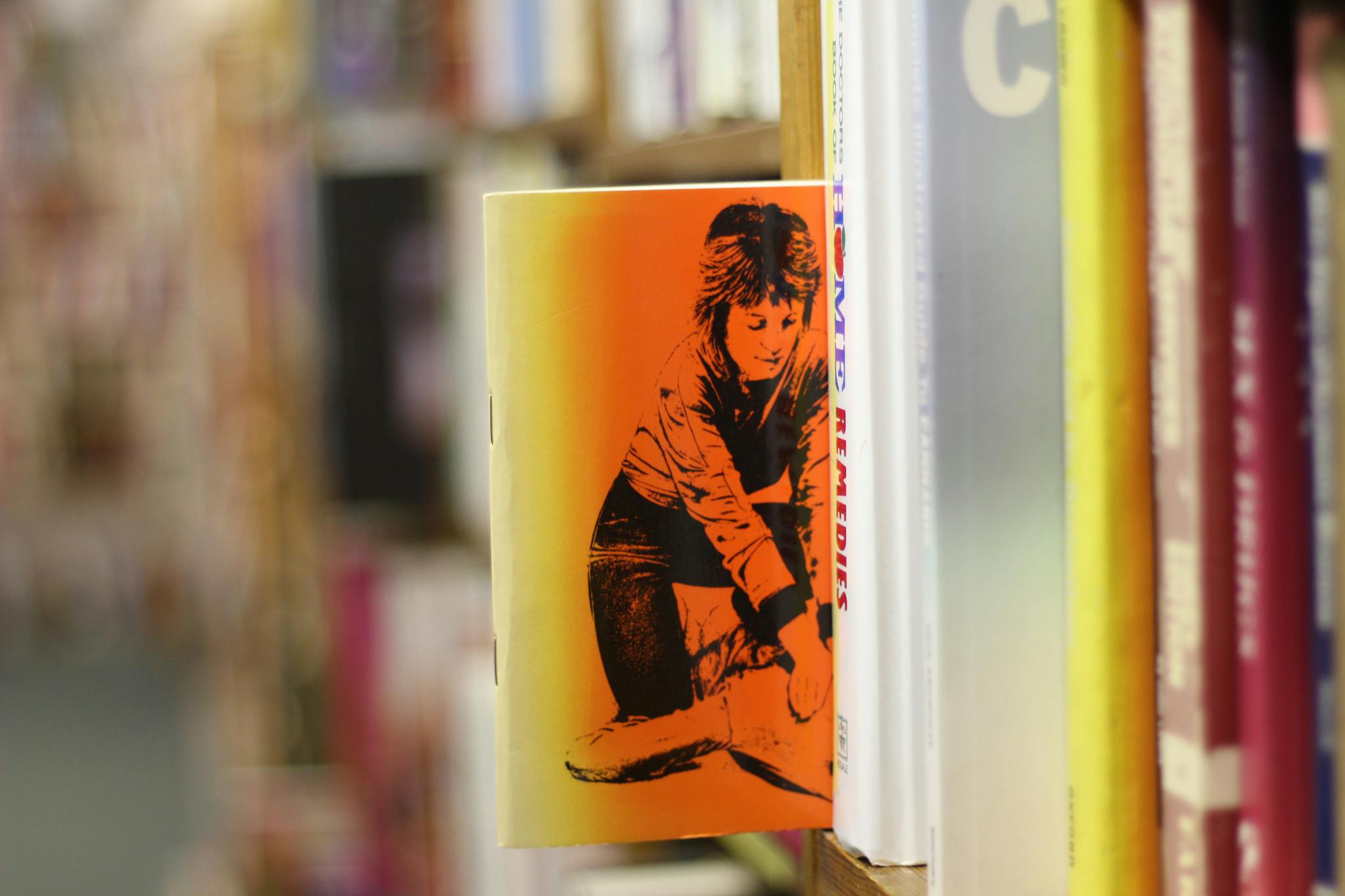 Vibrant book cover with an orange theme seen among wooden bookshelves in a cozy library.
